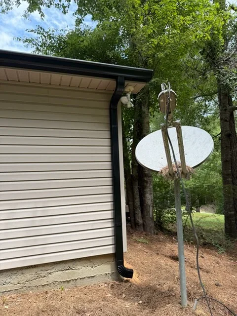 Black seamless gutters with white downspout extension on residential structure