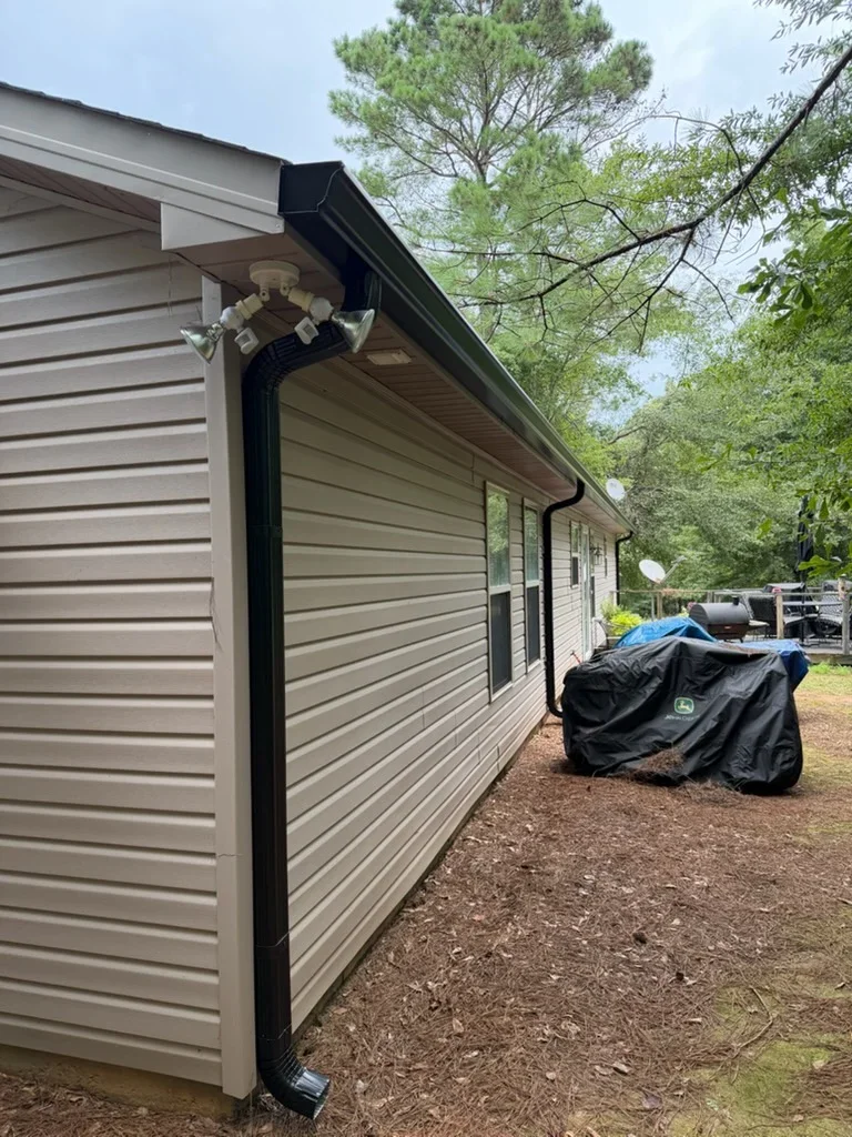 Black fascia and seamless gutter installation on residential home with tan siding