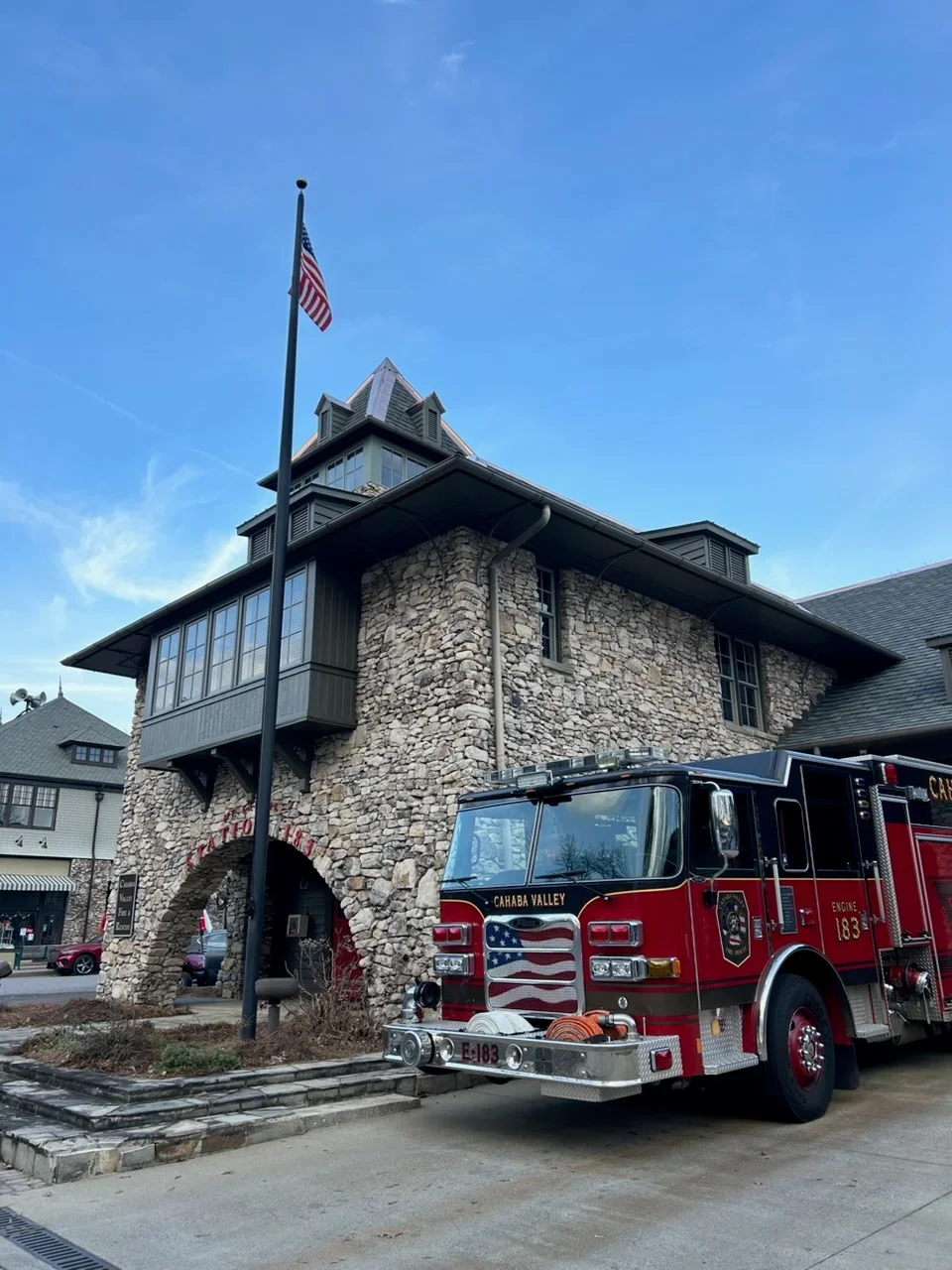Stone firehouse with new gutters installed on multi-level roof with dormers and cupola