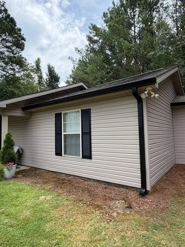 Light gray vinyl siding with black trim, gutters, and downspouts on residential home