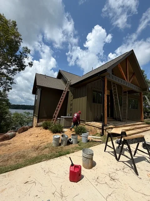 New gutter installation on lakeside home with board-and-batten siding during construction phase